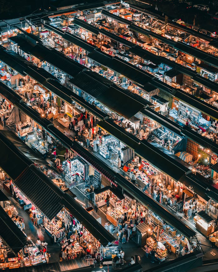 A bustling aerial view of a vibrant night market in Taiwan, showcasing diverse shopping stalls.